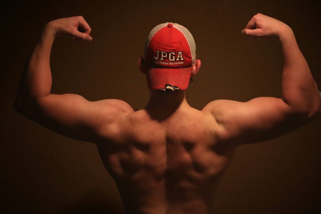 A man flexing his muscles in front of a brown background